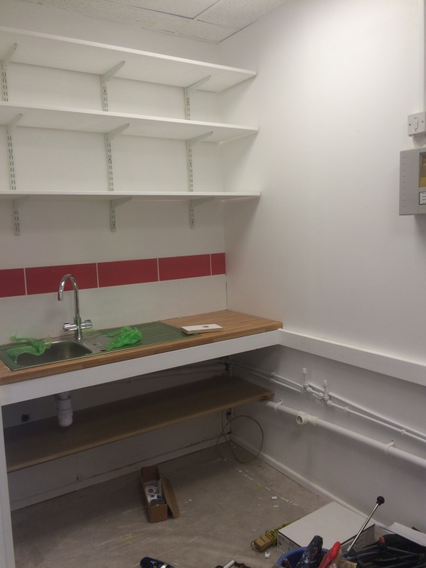 A splash of colour in the wash up area, with plenty of shelves for storage boxes above it.