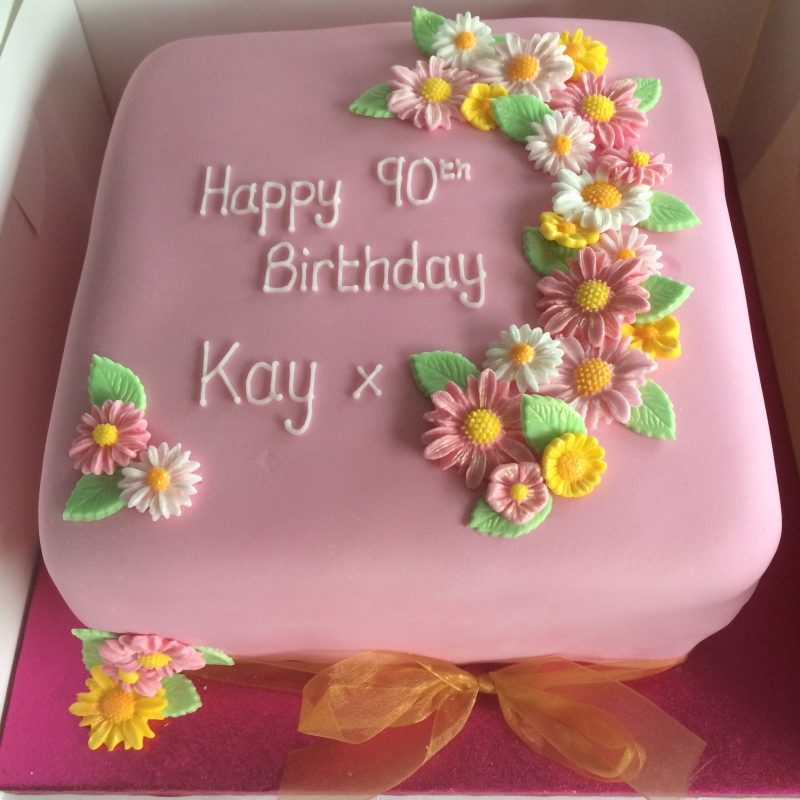 8" square cake filled with strawberry conserve and vanilla buttercream. Covered with more buttercream, fondant, and hand crafted sugar flowers. A round cake (24 slices)would cost from £45, the square version (32 slices) from £55.